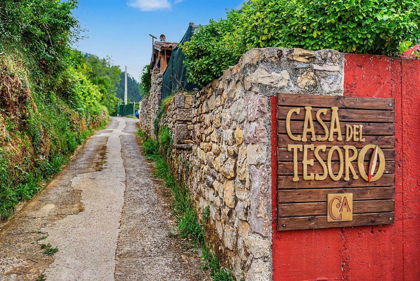Cartel de Casa del Tesoro en el portón rojo, junto al camino del pueblo