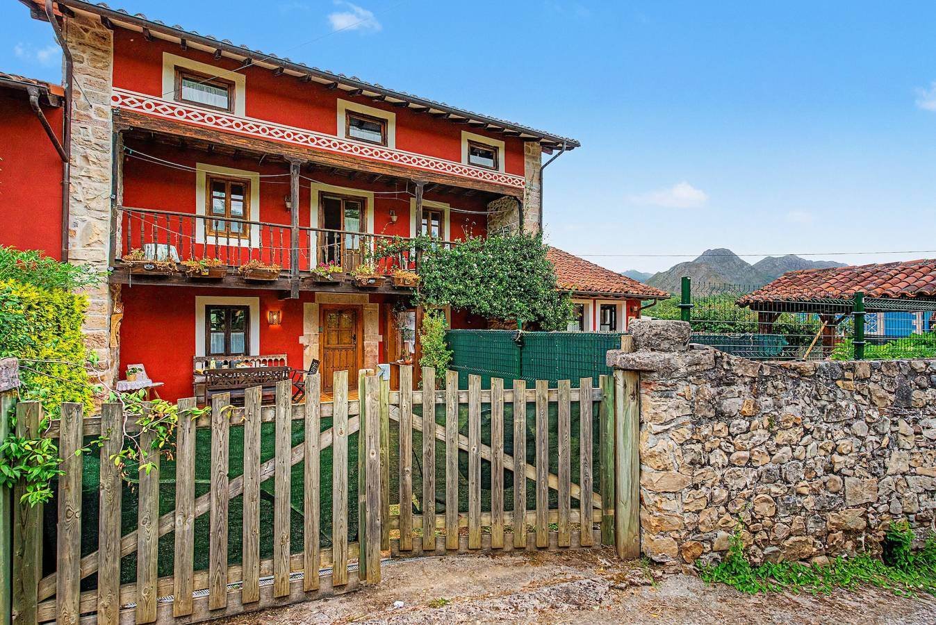Casa principal con portón de madera y muro de piedra