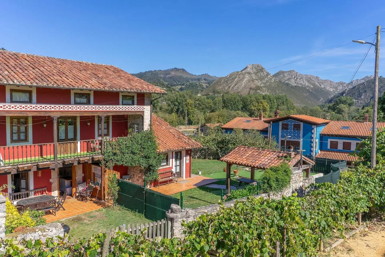 Vista elevada de las casas rojas de Casa del Tesoro con los Picos de Europa al fondo