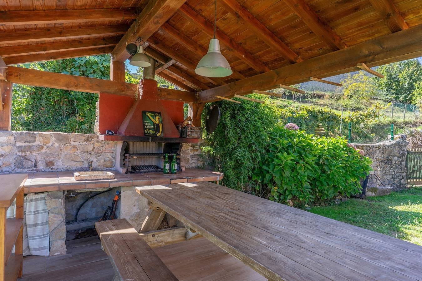 Merendero cubierto con mesa de madera y barbacoa de piedra