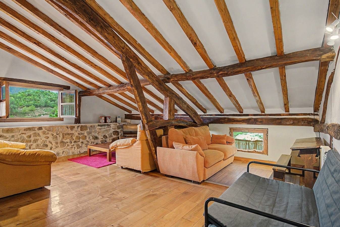 Sala de la buhardilla con sofás y vigas de madera