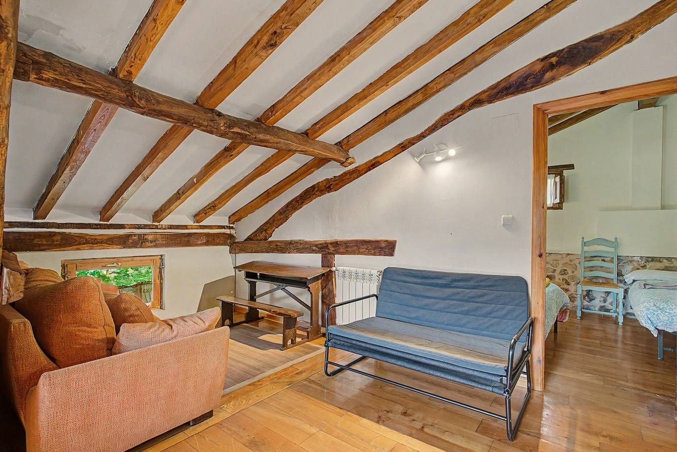 Sala de la buhardilla con sofás y puerta a un dormitorio