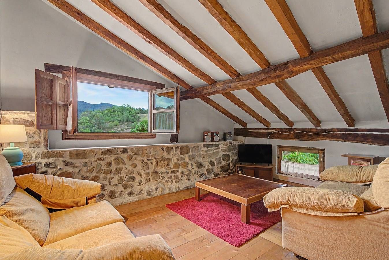 Sala de la buhardilla con vigas y vistas a la montaña