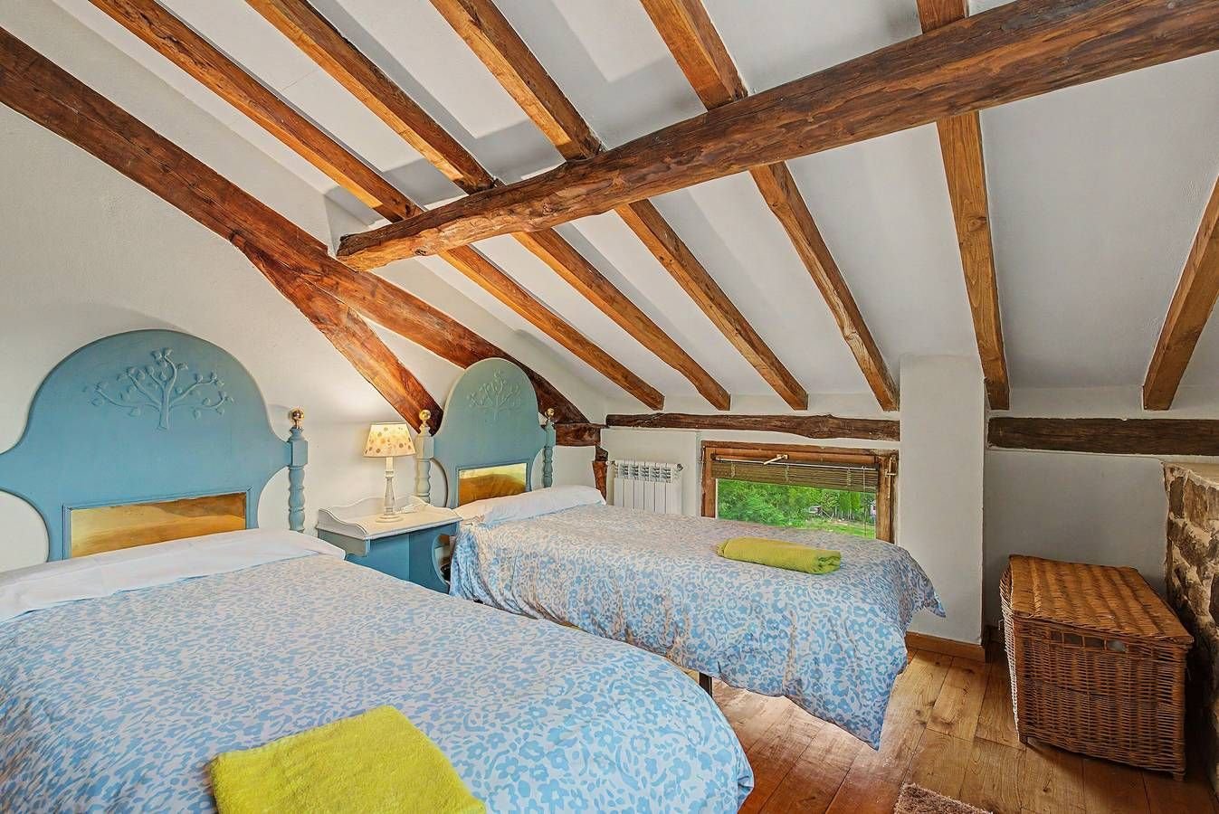 Dormitorio con colchas azules y vigas