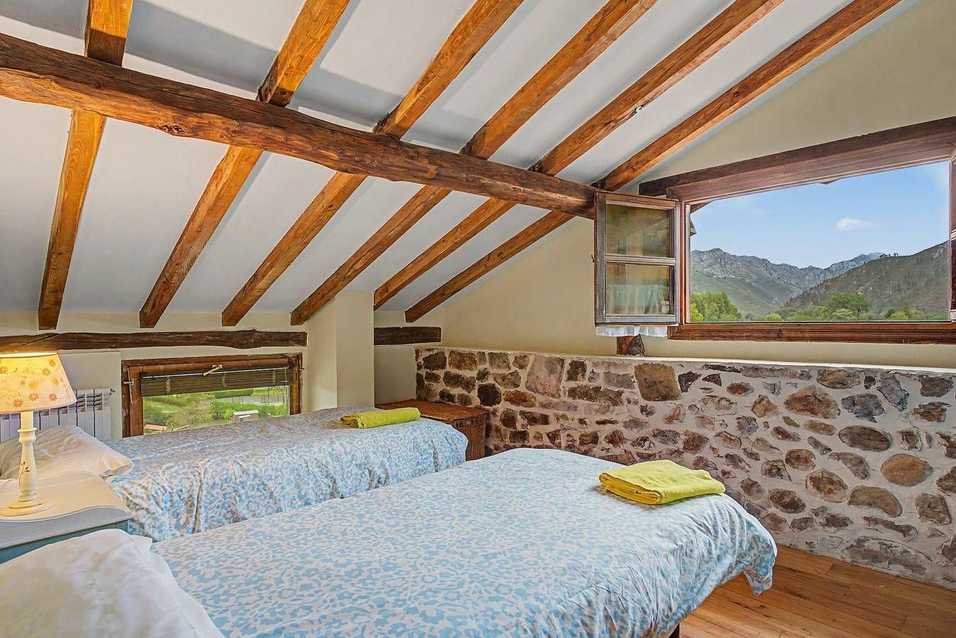 Dormitorio con camas bajo vigas y vistas a la montaña