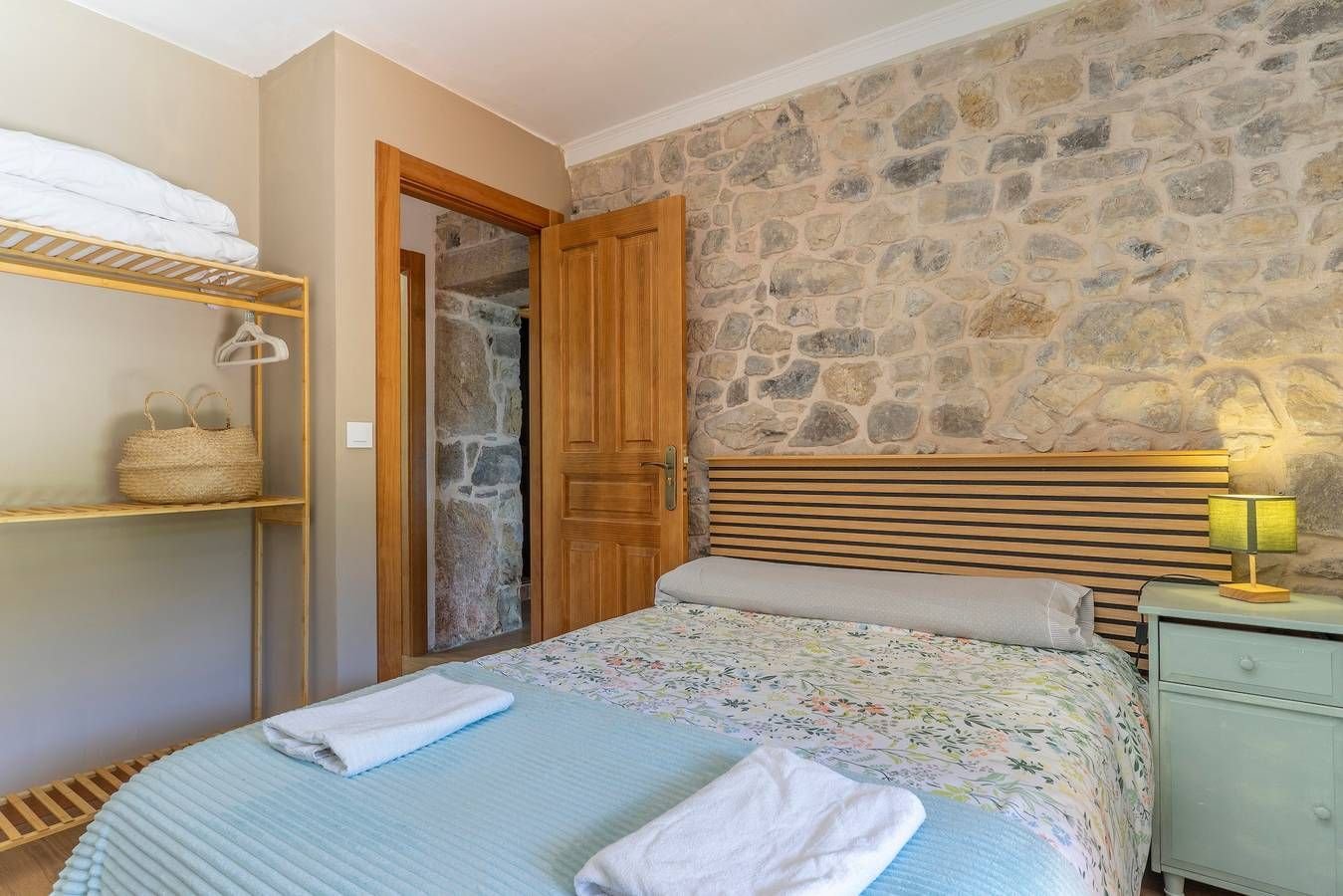 Dormitorio doble con estantes y pared de piedra