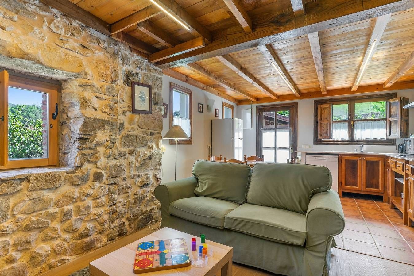 Salón con sofá verde y pared de piedra