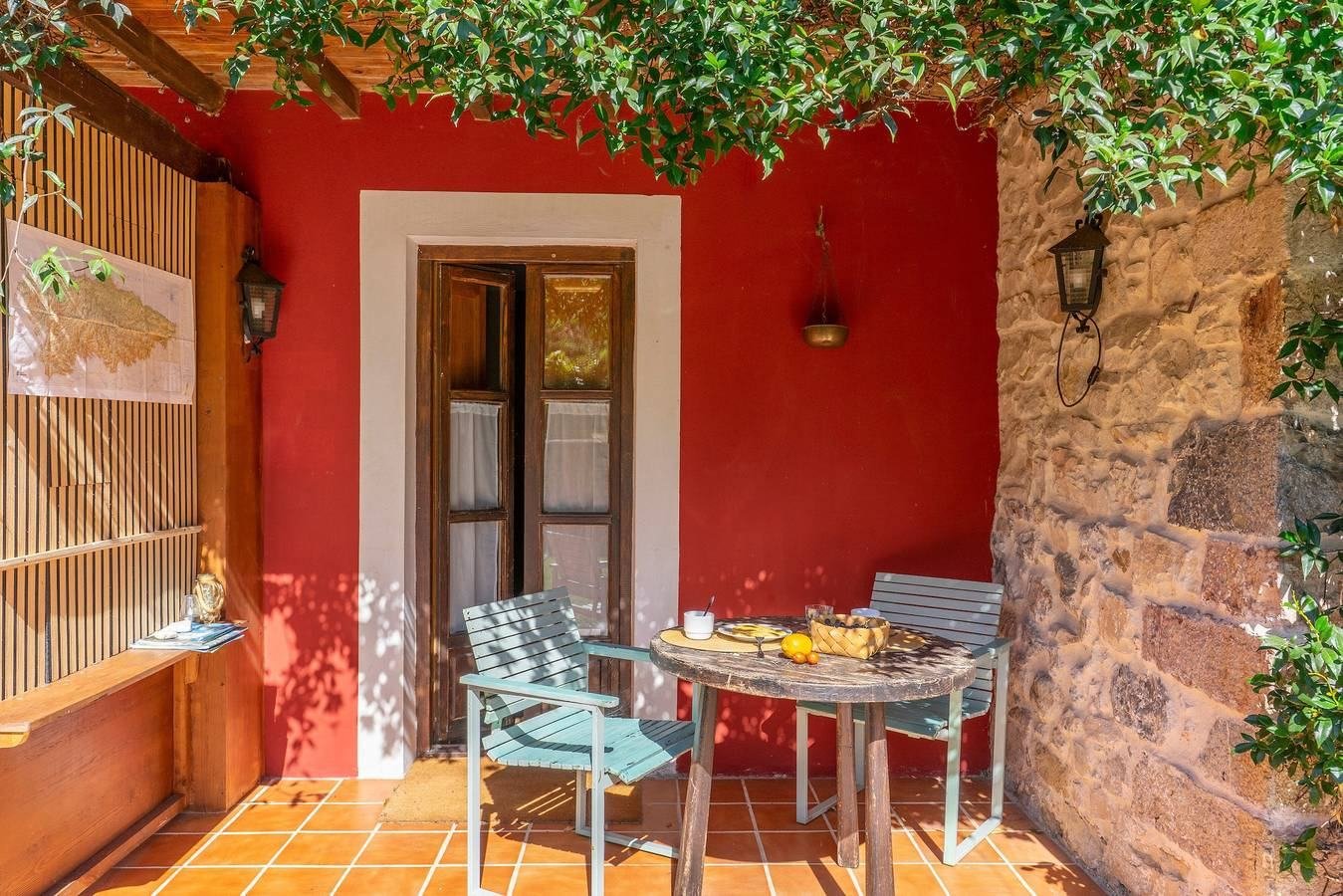 Terraza con pared roja, mesa y sillas
