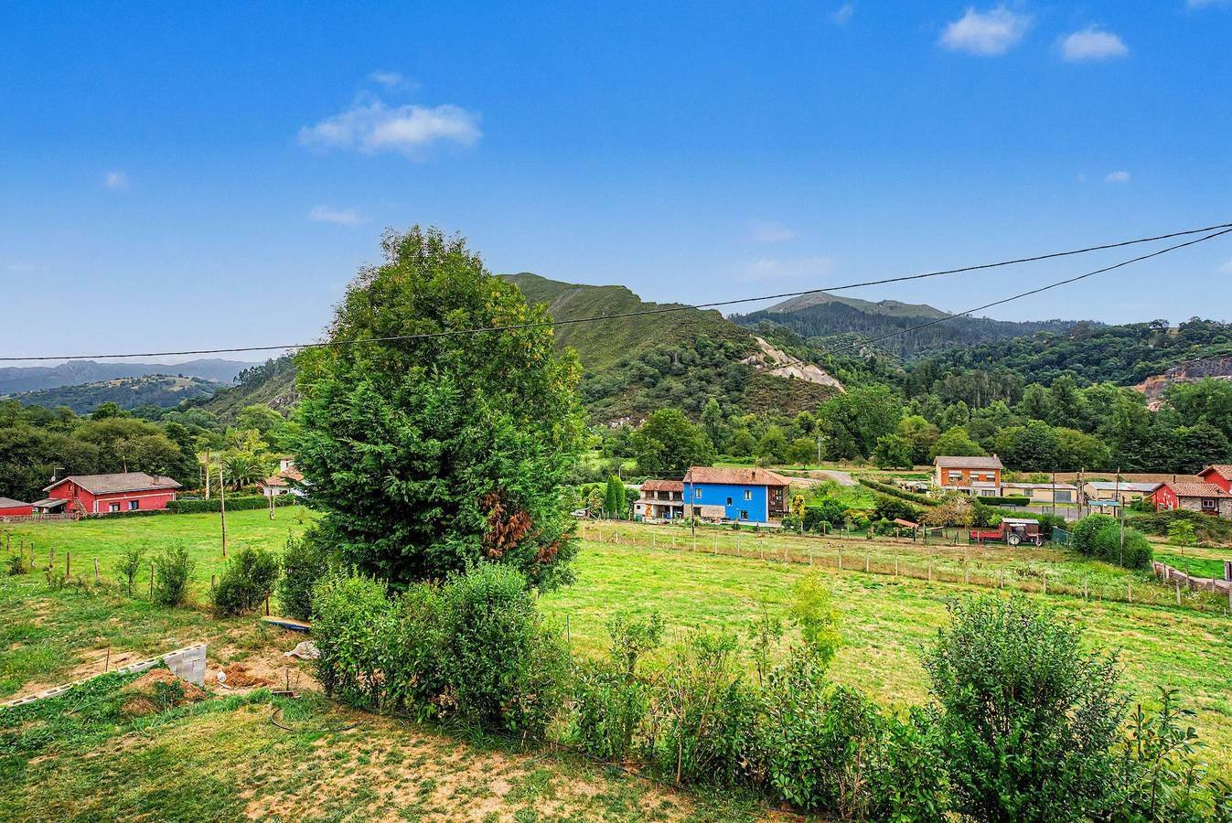Pradera, valle y montañas con casas a lo lejos